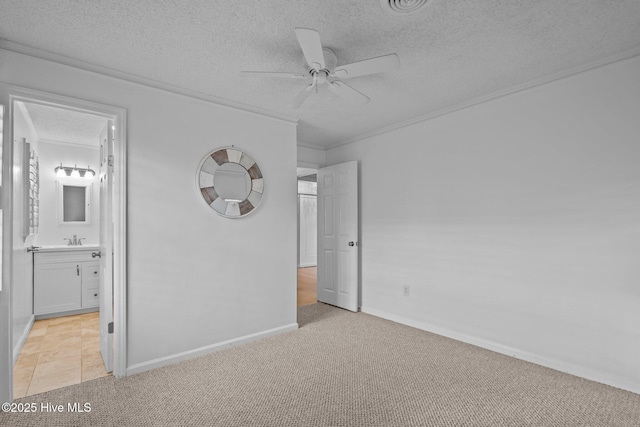 unfurnished bedroom featuring sink, ensuite bath, ornamental molding, a textured ceiling, and light colored carpet