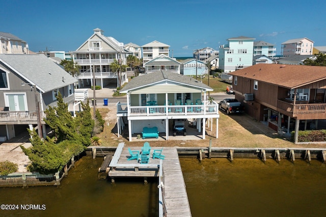 rear view of property with a deck with water view and a boat dock