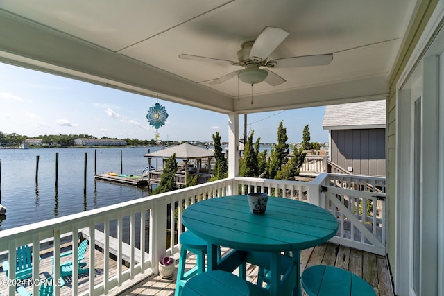 balcony featuring a boat dock, ceiling fan, and a water view