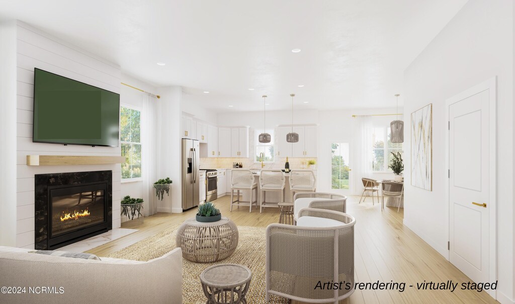 living room featuring light hardwood / wood-style flooring, a high end fireplace, and a healthy amount of sunlight