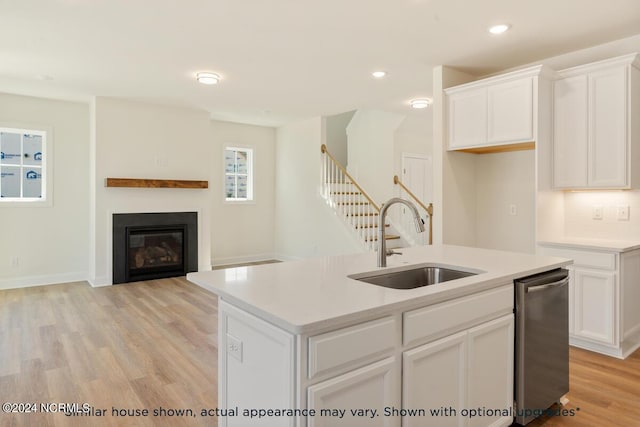 kitchen featuring sink, dishwasher, white cabinetry, an island with sink, and light wood-type flooring