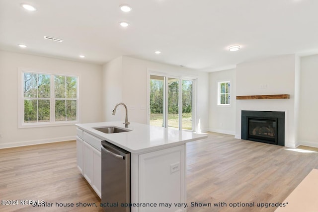 kitchen with sink, light hardwood / wood-style flooring, dishwasher, white cabinetry, and an island with sink