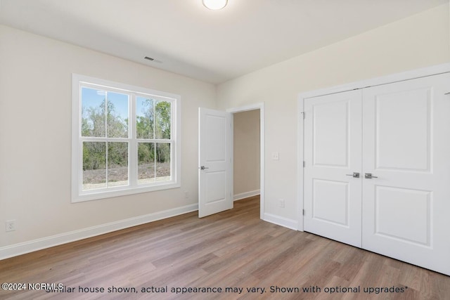 unfurnished bedroom with a closet and light wood-type flooring