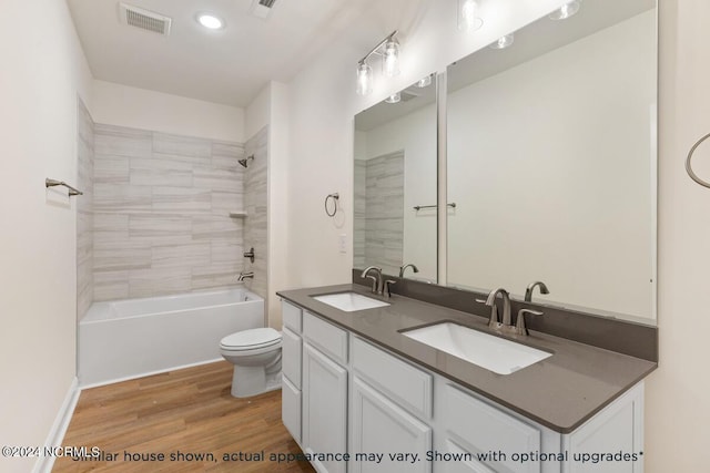 full bathroom featuring hardwood / wood-style flooring, tiled shower / bath, vanity, and toilet