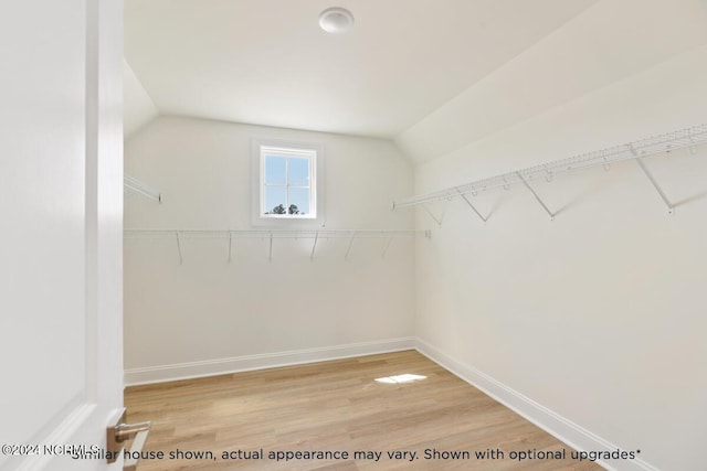 walk in closet featuring vaulted ceiling and light hardwood / wood-style floors