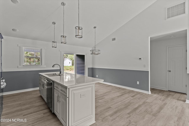 kitchen with sink, decorative light fixtures, a center island with sink, dishwasher, and light hardwood / wood-style floors