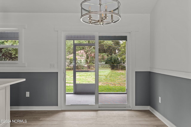 doorway to outside featuring a notable chandelier, wood-type flooring, and a wealth of natural light