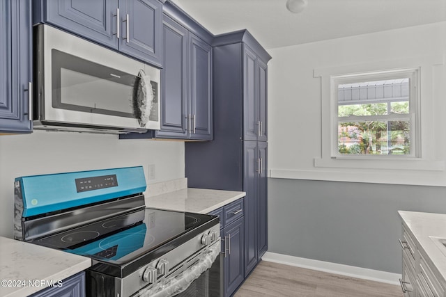 kitchen featuring blue cabinets, light stone countertops, appliances with stainless steel finishes, and light hardwood / wood-style flooring