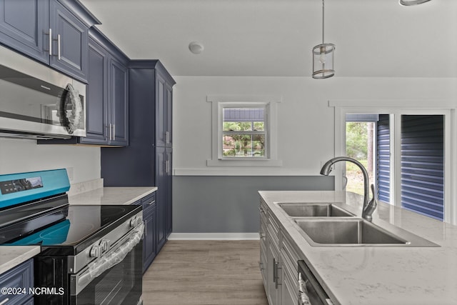 kitchen featuring decorative light fixtures, sink, stainless steel appliances, light stone countertops, and light hardwood / wood-style flooring