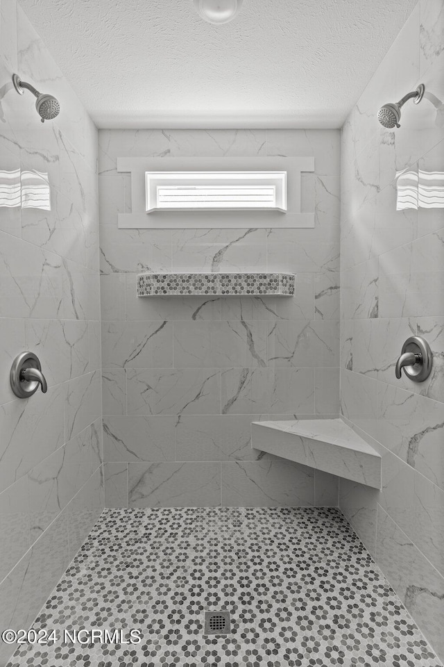 bathroom featuring a tile shower and a textured ceiling