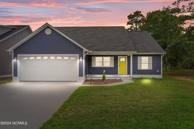 view of front facade with a garage, a shingled roof, concrete driveway, and a yard