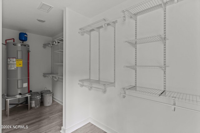 walk in closet with hardwood / wood-style flooring and water heater