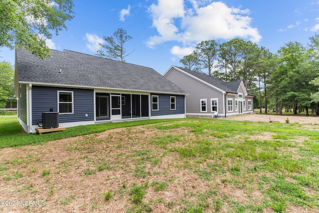 rear view of property featuring a lawn and central air condition unit