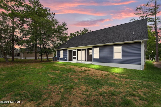 back house at dusk featuring a yard