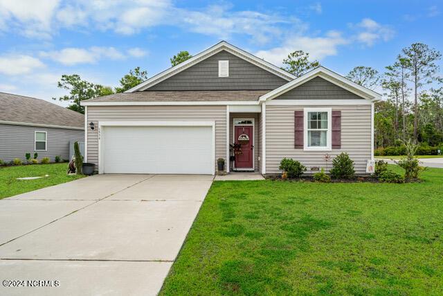 view of front of home with an attached garage, concrete driveway, and a front lawn
