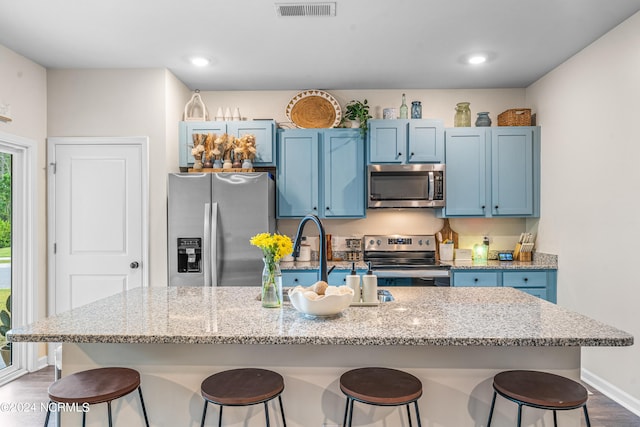 kitchen with blue cabinetry, stainless steel appliances, visible vents, and a breakfast bar area
