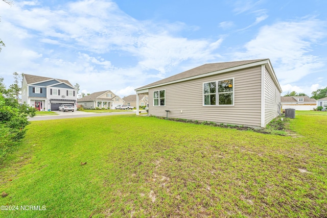 rear view of property featuring central air condition unit, a residential view, and a yard