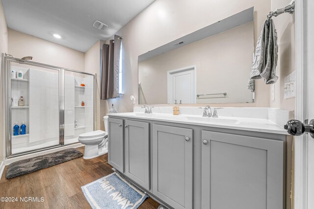 bathroom with vanity, toilet, hardwood / wood-style flooring, and a shower with door