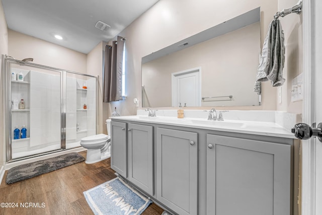 bathroom featuring wood finished floors, visible vents, a sink, a shower stall, and toilet
