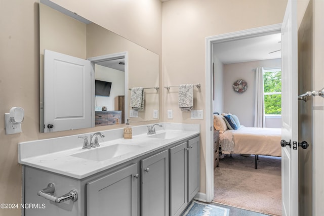 bathroom featuring double vanity, connected bathroom, and a sink