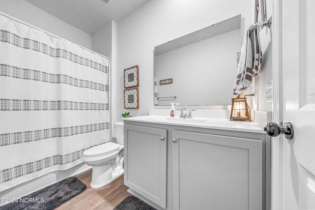 bathroom featuring vanity, toilet, hardwood / wood-style floors, and curtained shower