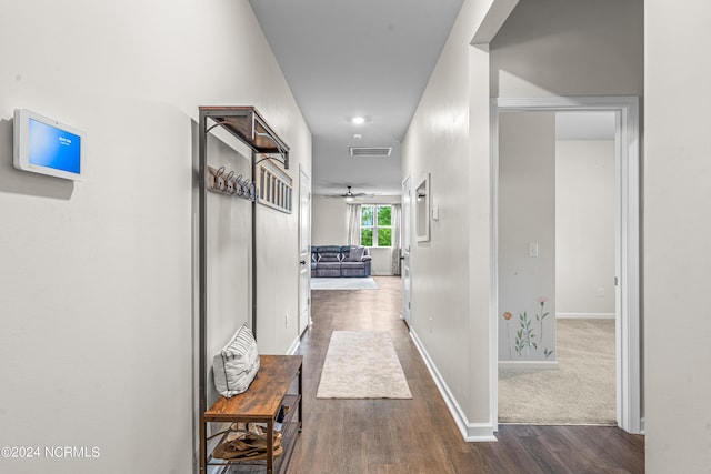 corridor featuring visible vents, baseboards, and wood finished floors
