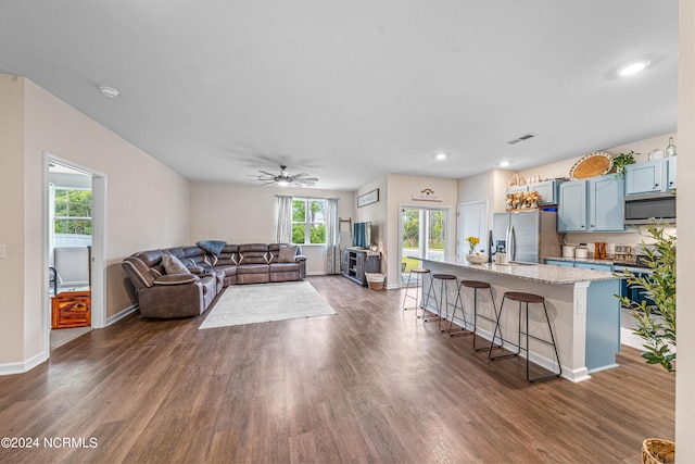 living room with dark wood finished floors, baseboards, visible vents, and ceiling fan