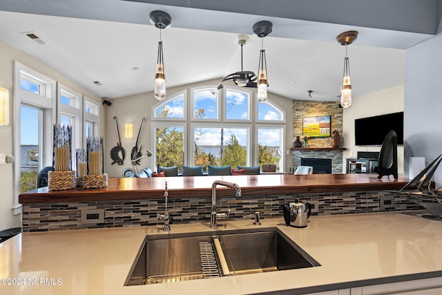 kitchen featuring pendant lighting, a fireplace, lofted ceiling, and sink