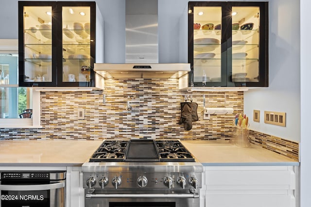 kitchen with high end range, backsplash, and wall chimney exhaust hood