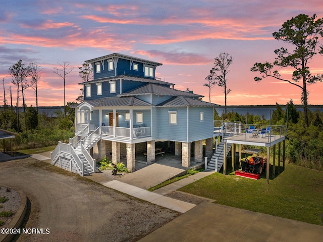 view of front of house with a carport, a porch, and a yard