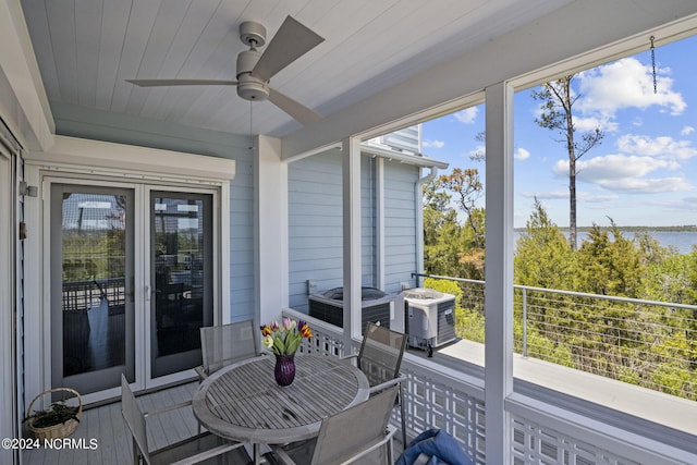 sunroom / solarium with ceiling fan and a water view