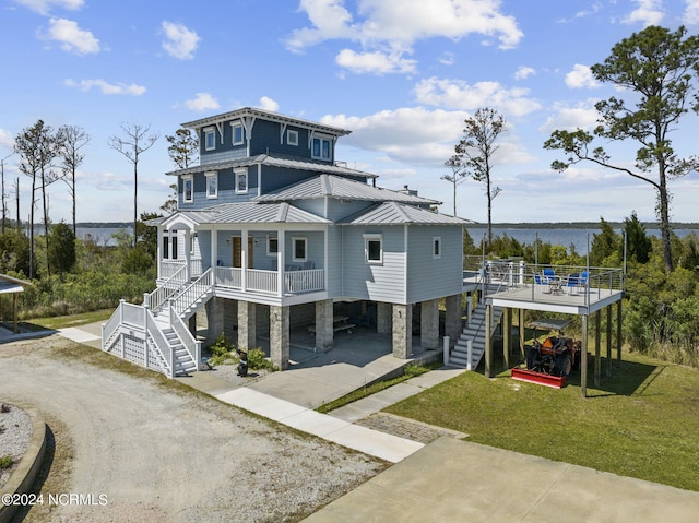 view of front of home featuring a front lawn, a water view, a porch, and a carport