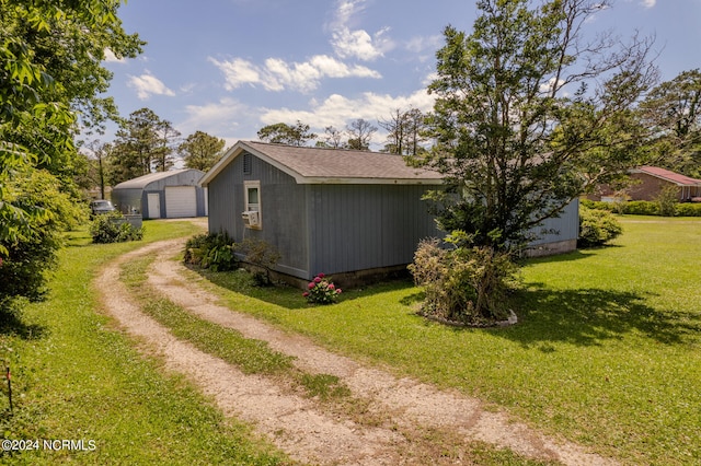 view of side of property featuring a garage, a lawn, and an outdoor structure