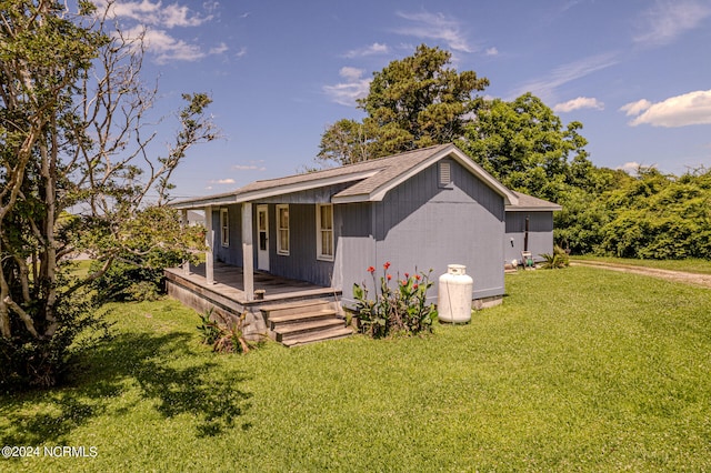 rear view of property featuring a yard and covered porch