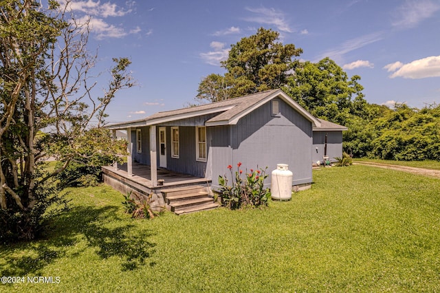 rear view of property with covered porch and a lawn