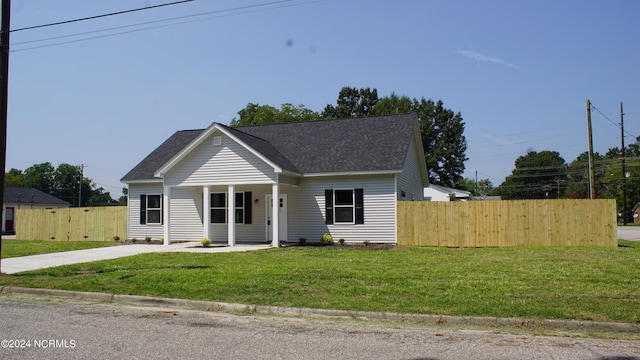 bungalow with a porch, a front yard, fence, and a shingled roof