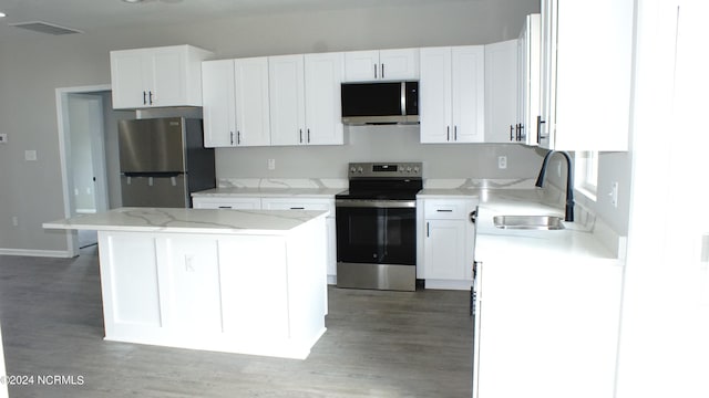 kitchen with appliances with stainless steel finishes, a sink, visible vents, and white cabinets