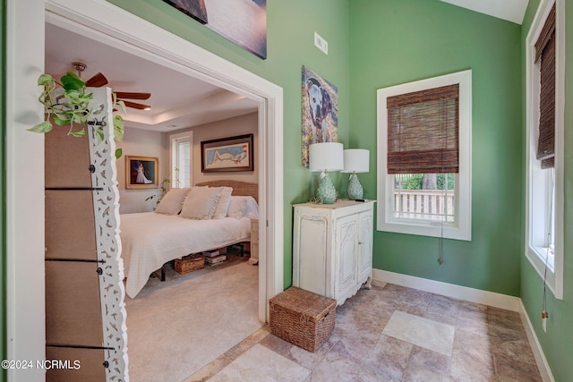 bedroom featuring a raised ceiling, light tile patterned floors, and ceiling fan