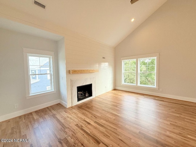 unfurnished living room featuring high vaulted ceiling, light hardwood / wood-style flooring, and a healthy amount of sunlight