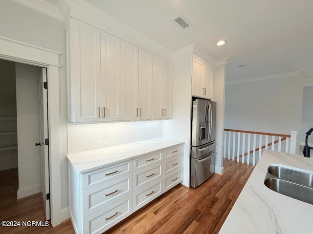 kitchen with tasteful backsplash, stainless steel fridge with ice dispenser, sink, white cabinets, and hardwood / wood-style floors