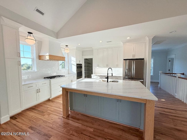 kitchen featuring a large island, stainless steel appliances, white cabinets, custom range hood, and light wood-type flooring