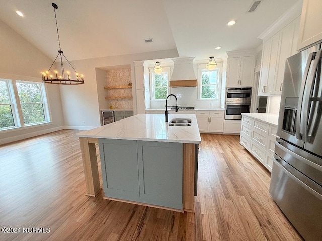 kitchen featuring white cabinets, lofted ceiling, a kitchen island with sink, and appliances with stainless steel finishes