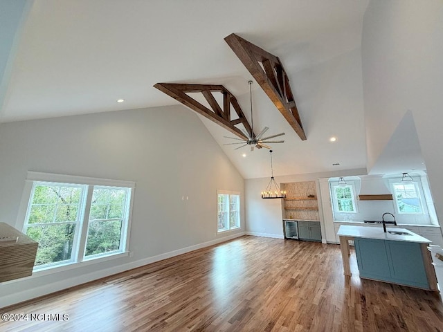 unfurnished living room with high vaulted ceiling, light hardwood / wood-style floors, sink, and a wealth of natural light