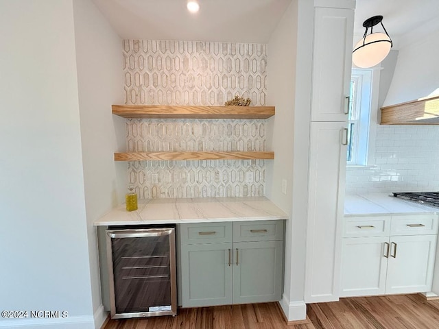 bar with custom exhaust hood, light hardwood / wood-style flooring, tasteful backsplash, light stone counters, and beverage cooler