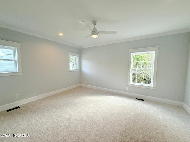 carpeted spare room with crown molding, ceiling fan, and a healthy amount of sunlight