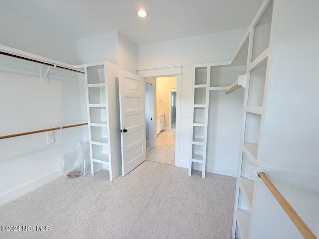 spacious closet featuring light colored carpet