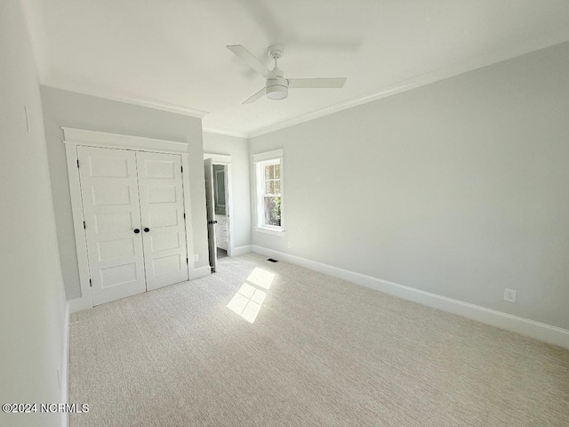 unfurnished bedroom with ceiling fan, crown molding, light carpet, and a closet