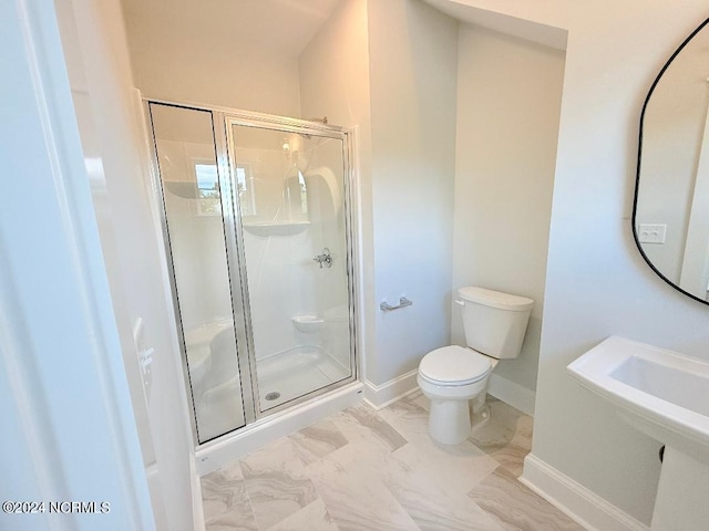 bathroom featuring a shower with door and toilet