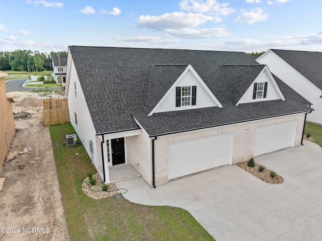 modern farmhouse with central air condition unit, a shingled roof, fence, and concrete driveway