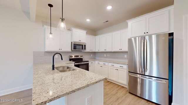 kitchen with appliances with stainless steel finishes, backsplash, a sink, and a peninsula